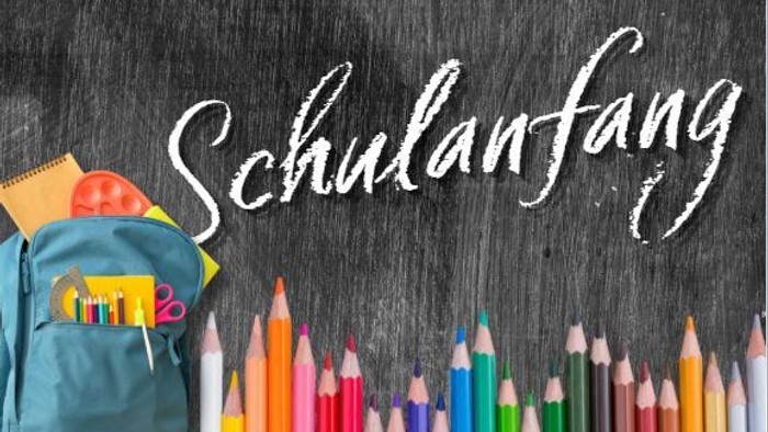 Rückkehr-zu-Schule-Szene mit Kreidetafelaufschrift „Schulanfang“ und bunten Schulutensilien.