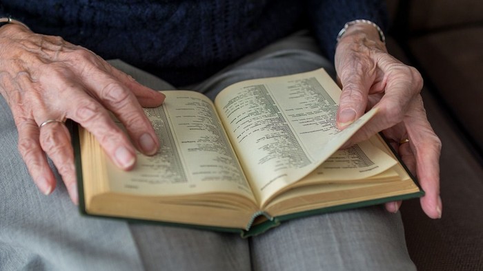 Alte Hände halten aufgeschlagenes Buch