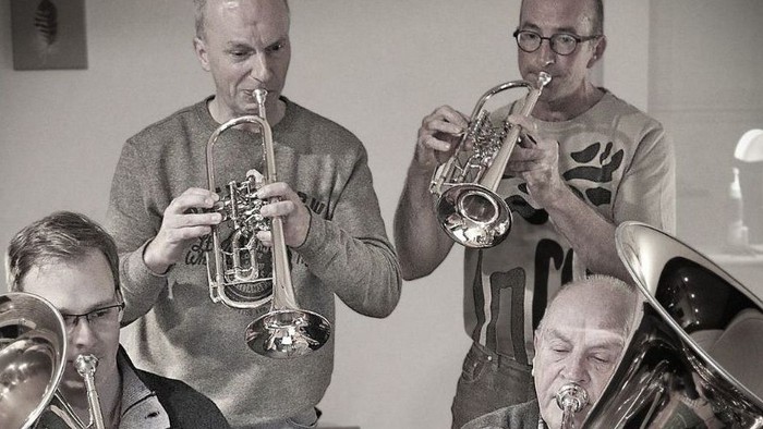 Eine Gruppe von Musiker:innen, die gemeinsam Blasinstrumente in einer Probe oder bei einer Aufführung spielen.