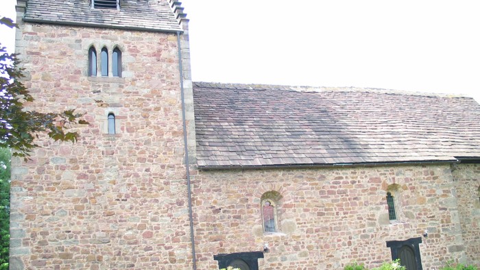 Außenansicht der evangelischen Kirche in Vaake. Natursteingebäude mit hohem rechteckigem Turm.