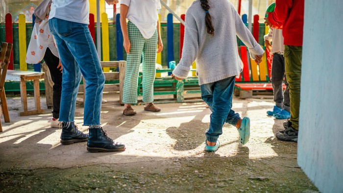 Kinder, die auf einem Spielplatz mit buntem Spielgerät spielen und laufen, tragen Outdoor-Schuhe.