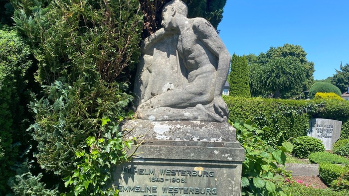 Grabmal mit Skulptur in parkähnlichem Friedhof
