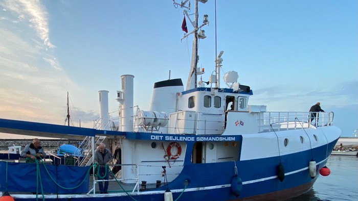 Et blå og hvid fiskeskib ved kajen med navnet