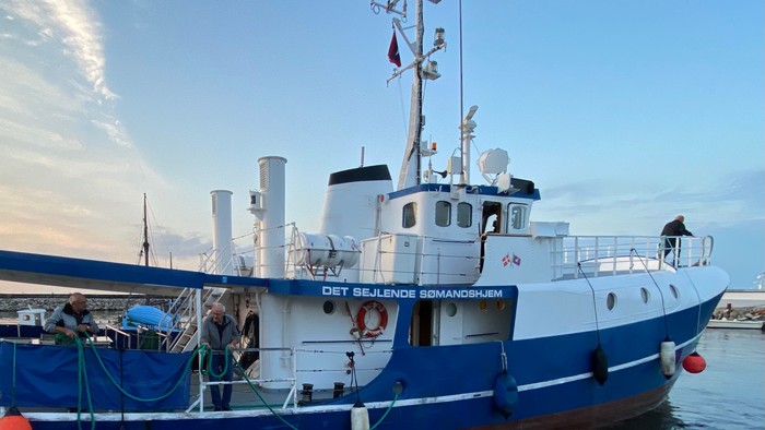 Et blå og hvid fiskeskib ved kajen med navnet 