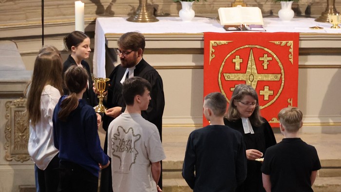 Kinder und Priester in Kirche vor Altar