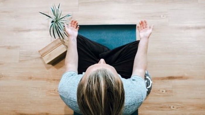Frau meditiert auf einem Yogamatte in einem ruhigen Raum