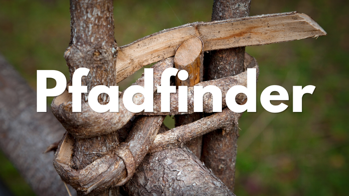 Ein rustikales Holzschild mit dem Wort „Pfadfinder“, das an einem Baumast im Freien befestigt ist.