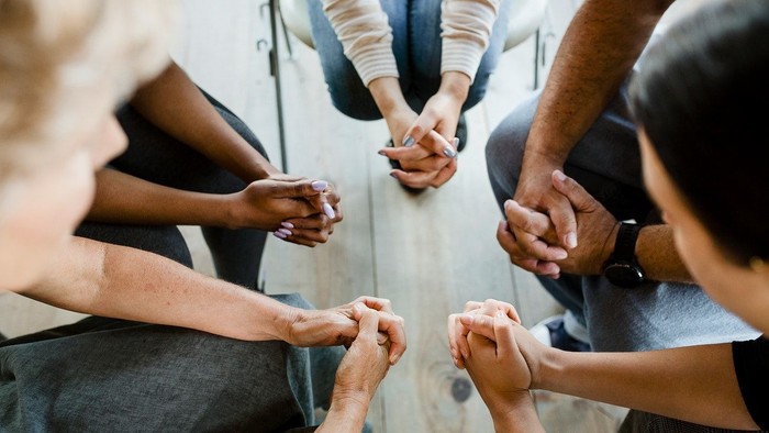 People holding hands in a circle, showing unity and support.