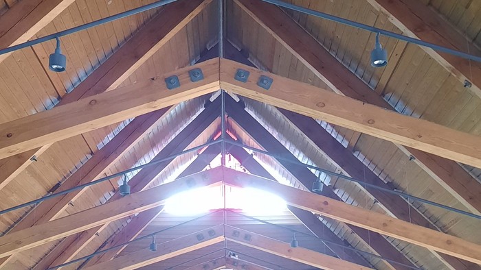 Indre del af en stor kirke med høje træbalker og lysende lys.