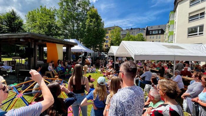 Viele Menschen bei einem Freiluft-Event mit Zelten und Musikbühne