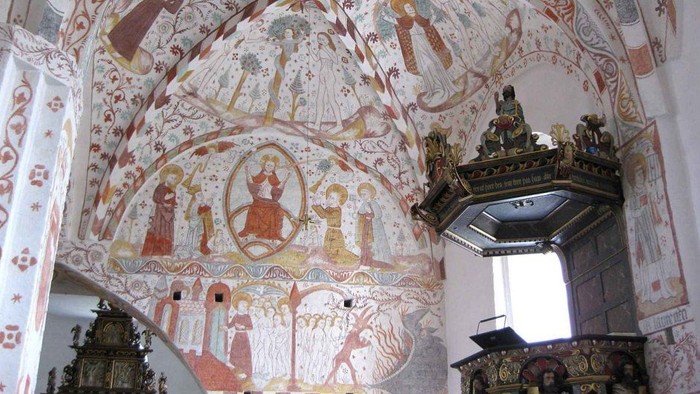 Indviklede freskoer og prægtige alterudsmykninger pryder loftet og prædikestolen i en historisk kapel.