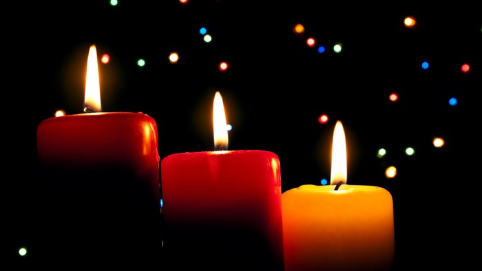 Tre lysende lysekander på sort baggrund med farverne rød og gul.