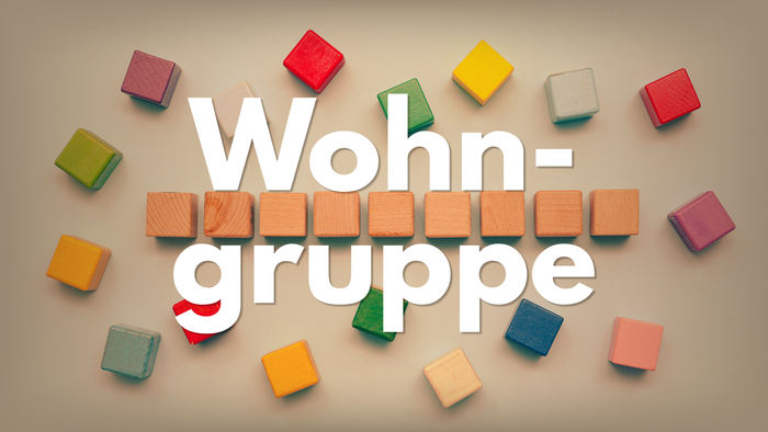 Bunte Holzklötze bilden das Wort „Wohngruppe“ auf Deutsch und symbolisieren damit das Konzept einer Wohn- oder Lebensgemeinschaft.
