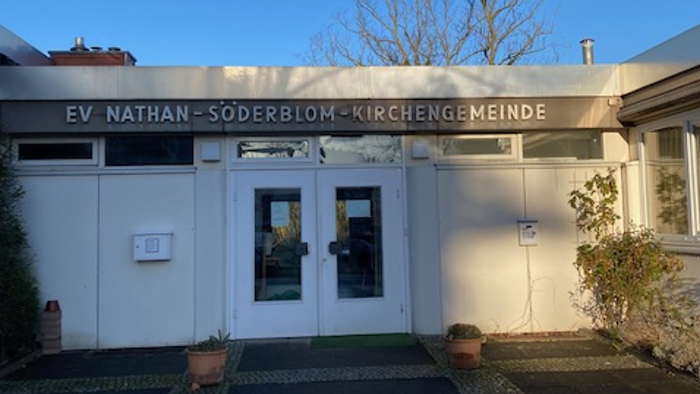 Das Gebäude der EV Nathan-Söderblom-Kirchengemeinde mit Eingangstür und Topfblumen.