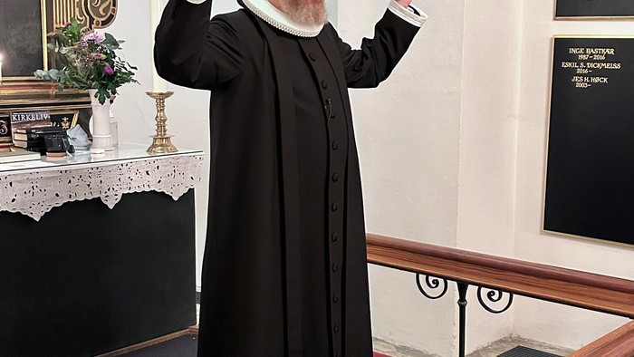 Mand i svart kapittel i kirke.