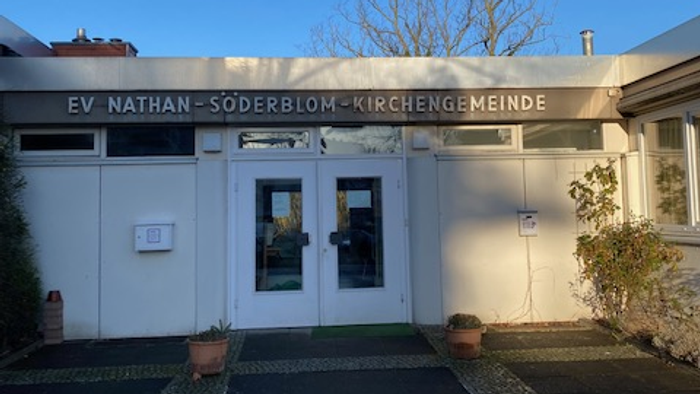 Das Gebäude der EV Nathan-Söderblom-Kirchengemeinde mit Eingangstür und Topfblumen.