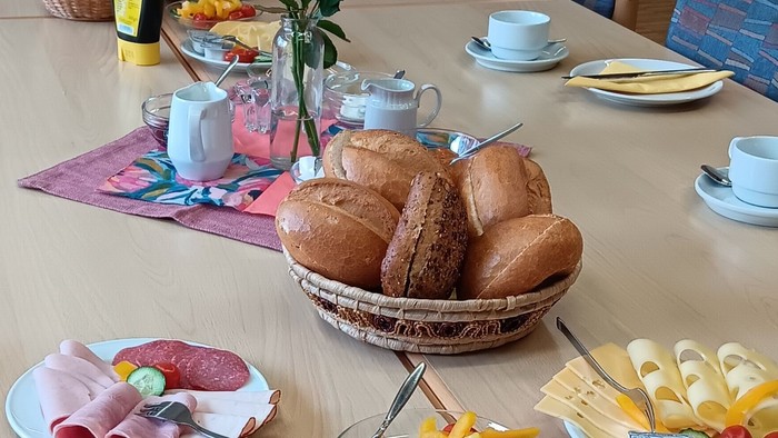 Frühstückstisch mit Brot, Wurst, Gemüse und Tee