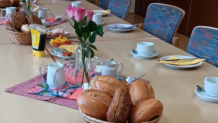 Frühstückstisch mit Brot, Wurst, Gemüse und Tee
