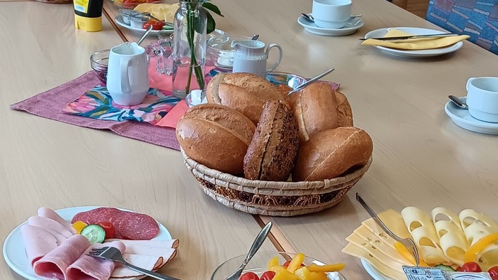 Frühstückstisch mit Brot, Wurst, Gemüse und Tee