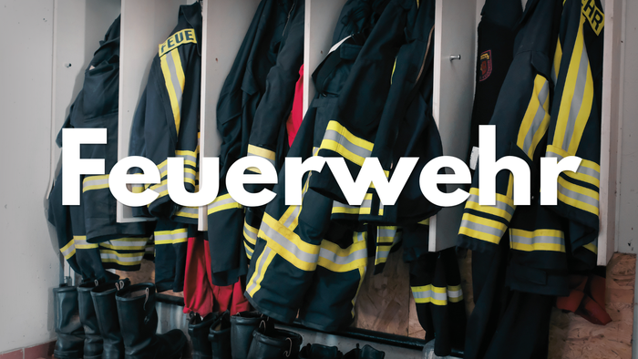 Feuerwehrausrüstung und Jacken mit der Aufschrift „Feuerwehr“, die ordentlich in einem Abstellschrank hängen.
