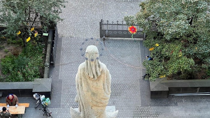 Die Statue eines Mannes sitzt in einem Innenhof mit Kopf in den Händen.