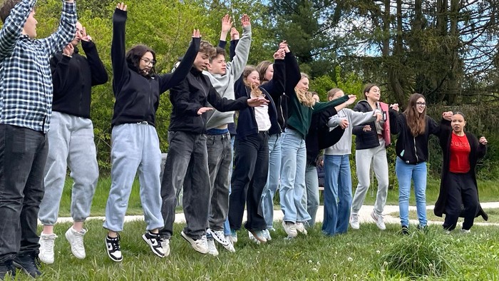 Gruppe von Menschen, die fröhlich an einer Outdoor-High-Five-Aktion auf einer Rasenfläche teilnehmen.
