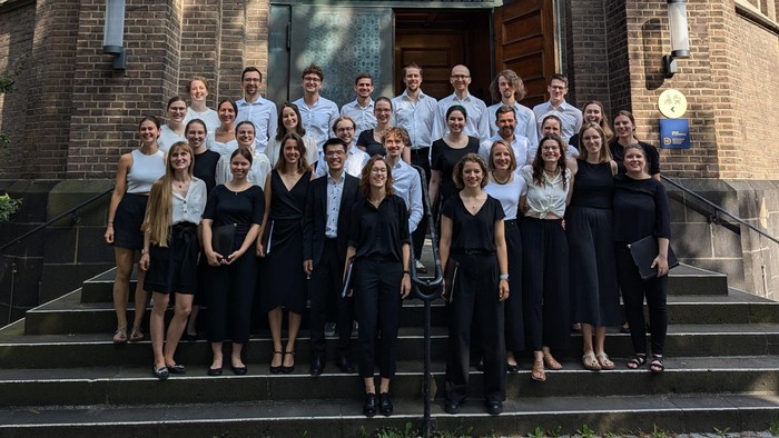 Auf der Treppe vor einer Kirche stehen die Mitglieder des Chores Status idem