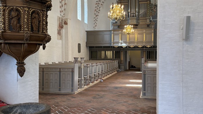 Indgang til en stor kirke med høje vægge og orgel.