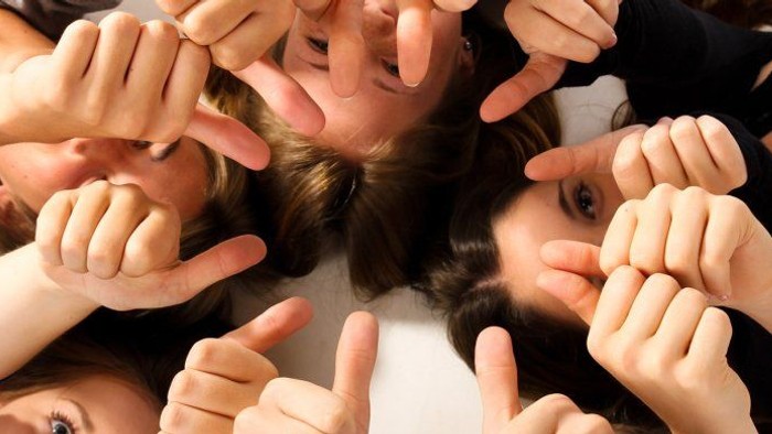 Menschen, die mit zusammengelegten Händen ein Daumen-hoch-Zeichen zeigen