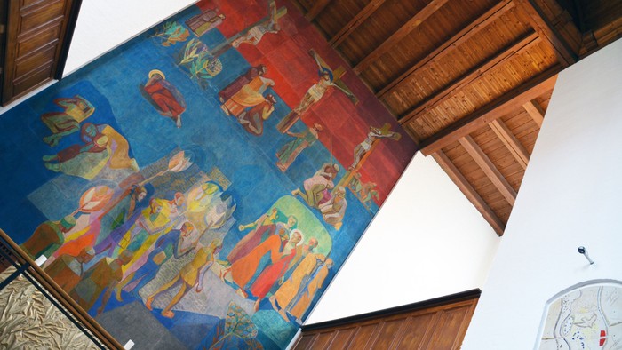Farverigt vægmaleri, der skildrer farverige religiøse eller historiske figurer under trælofter.