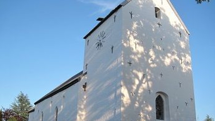 Et hvidt kirkebygning med klokketårn og en lille portal.