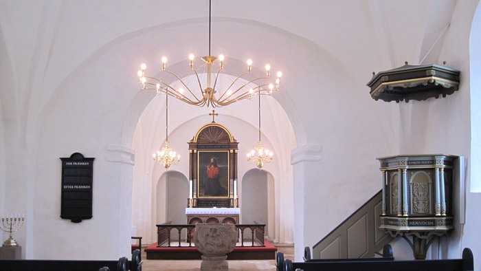 Indre del af kirke med alter, lysstake og orgel