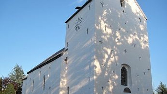 Et hvidt kirkebygning med klokketårn og en lille portal.