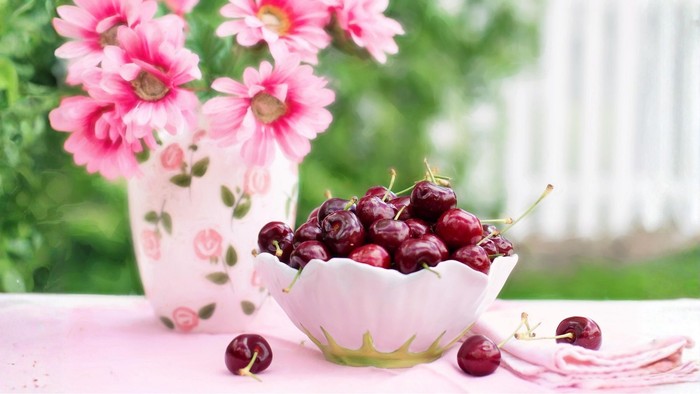 Vase mit pinken Blumen, Schale mit Kirschen