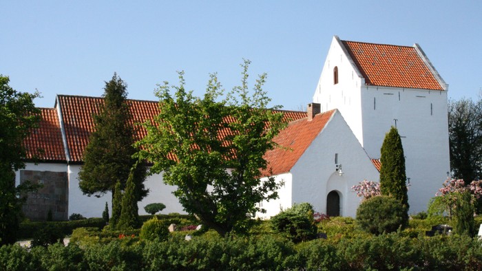 Hvid kirke med røde tag og grønne træer