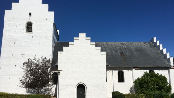Hvid kirke med spids tak og smukt indgang.