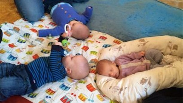 To børn ligger på en dekke med et blå dyr og en blå pude.