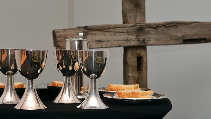 Silberne Weingläser und Käse auf schwarzem Tisch vor Holz.