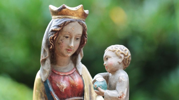 Maria als Königin hält das Jesuskid im Arm, das die Welt in den Händen hält. Grüner frischer Hintergrund im Frühling