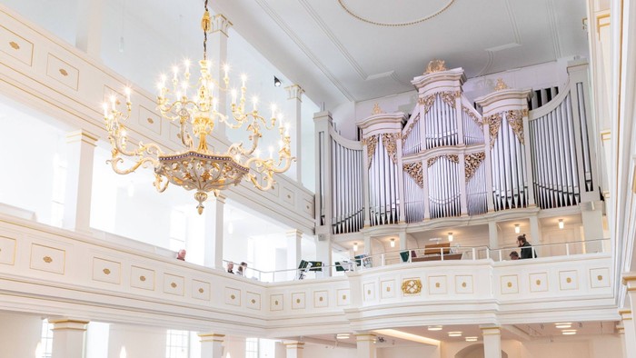Ein prächtiger Ballsaal mit einem großen Kronleuchter und einer Orgel auf einer Empore