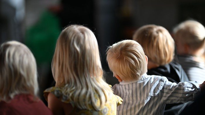 Eine Gruppe von Kindern, die eng beieinanderstehen und nach vorne blicken, mit unscharfem Hintergrund.