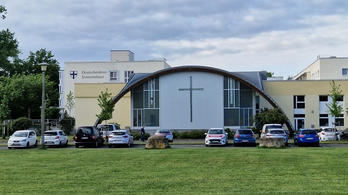 Kirche mit großem Kreuz und geparkten Autos davor