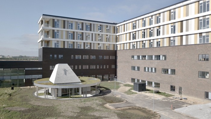 Det er et moderne boligkompleks med flere bygninger og en central plads.