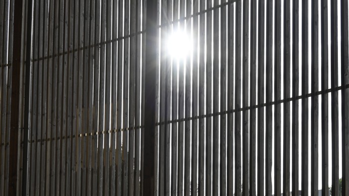 Das Bild zeigt einen Flur mit Gittern und Lichtstrahlen.