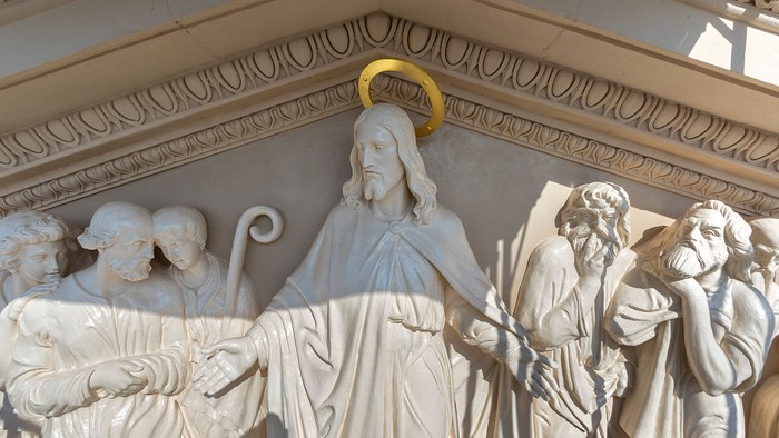 Die Skulptur zeigt Jesus Christus mit Jüngern, umgeben von architektonischen Details.