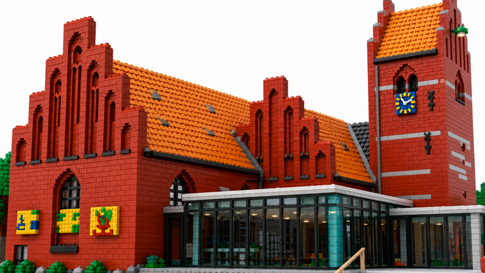 Et detaljeret LEGO-model af en historisk murstensbygning i rødt tegl med et urtårn og dekorative vinduer.