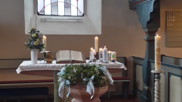 Eleganter Kirchenaltar mit Kerzen, Blumen und einem Buntglas-Kruzifixfenster in einer besinnlichen Kapelle.