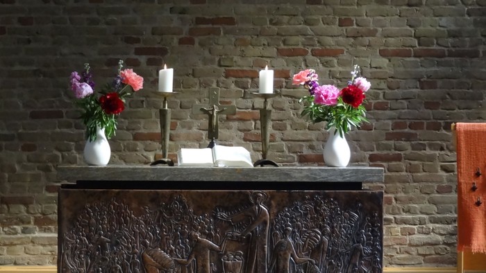 Blumenvasen und Kerzen auf einem Tisch vor Ziegelwand