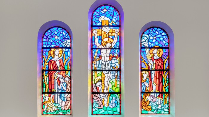 Tre farverige glasvinduer med religiøse motiv i bueform
