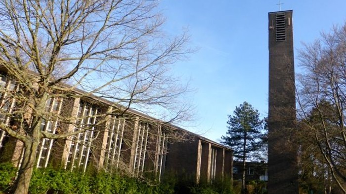 Moderner Campusbau mit hohem, einzigartigem Glockenturm in einer begrünten Rasenfläche.